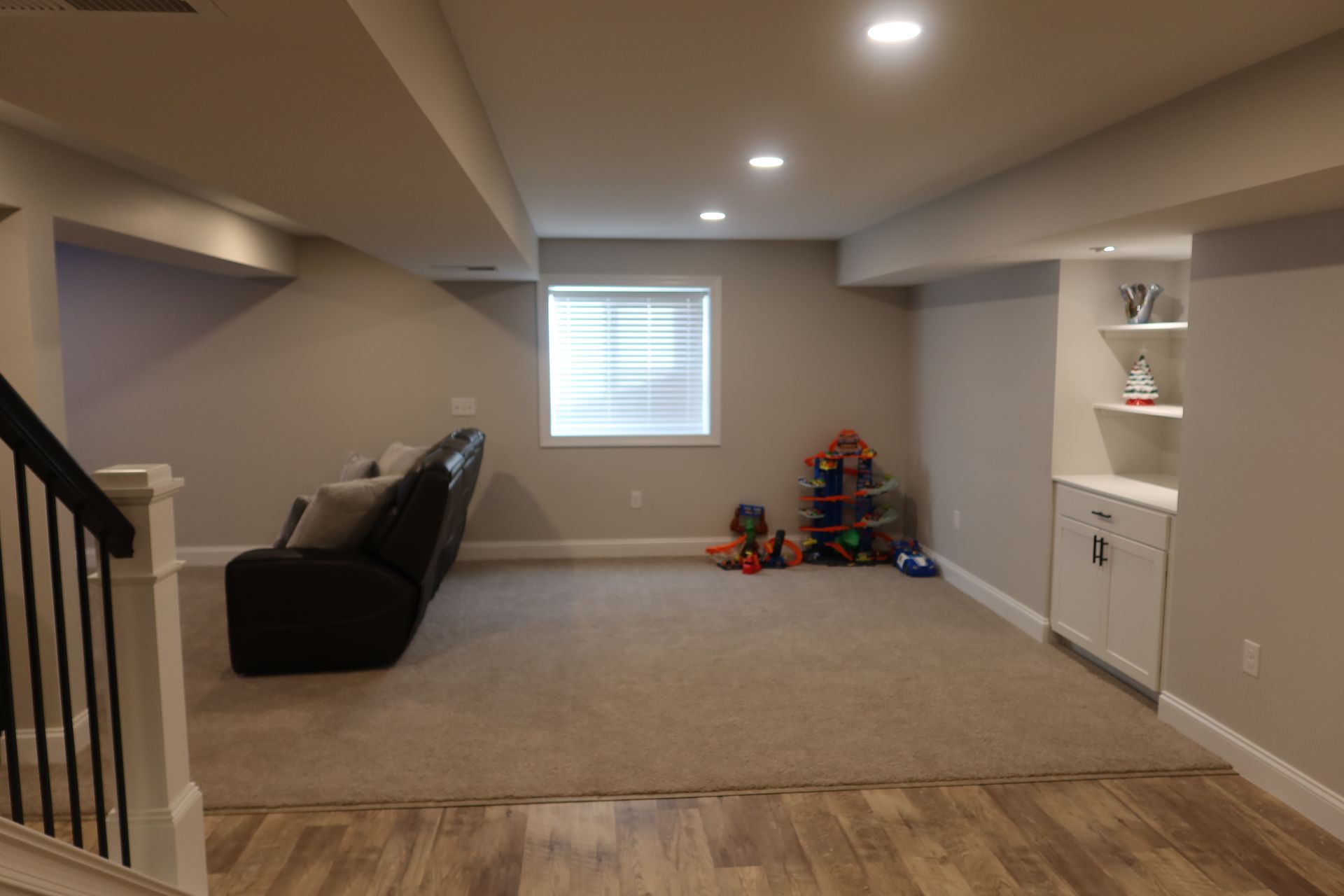 A basement with a couch , stairs and a window.