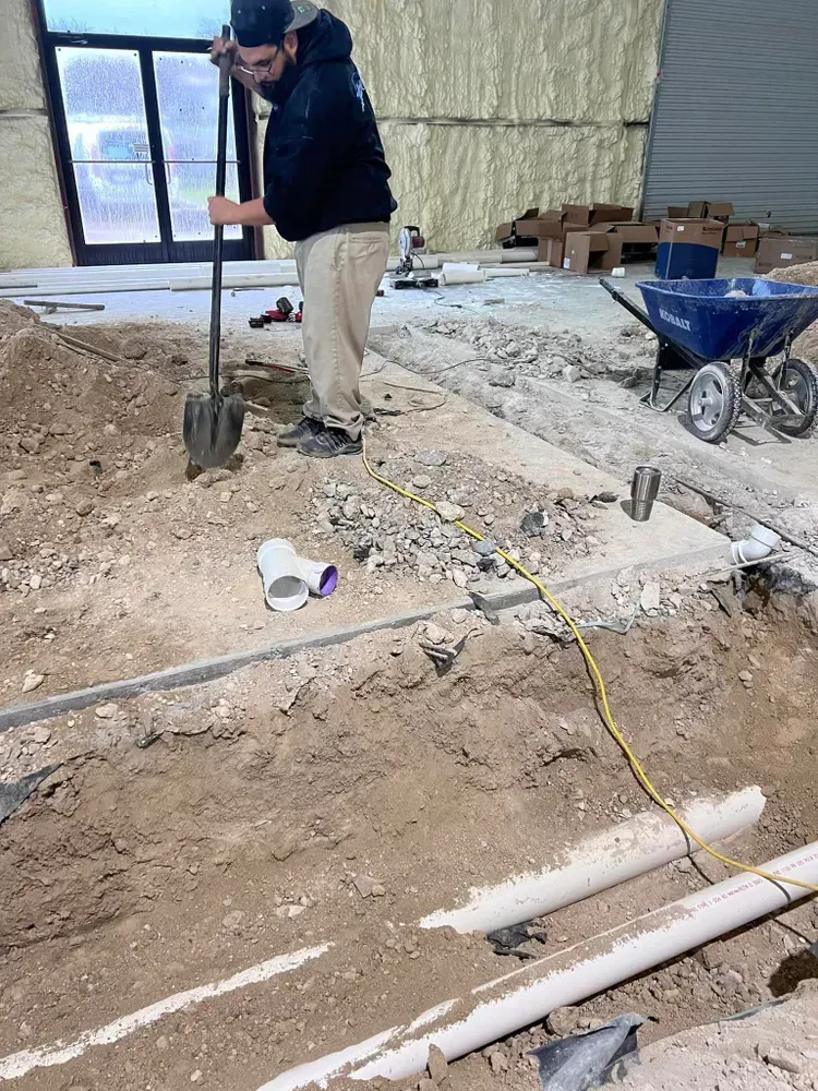 A man is digging a hole in the ground with a shovel.