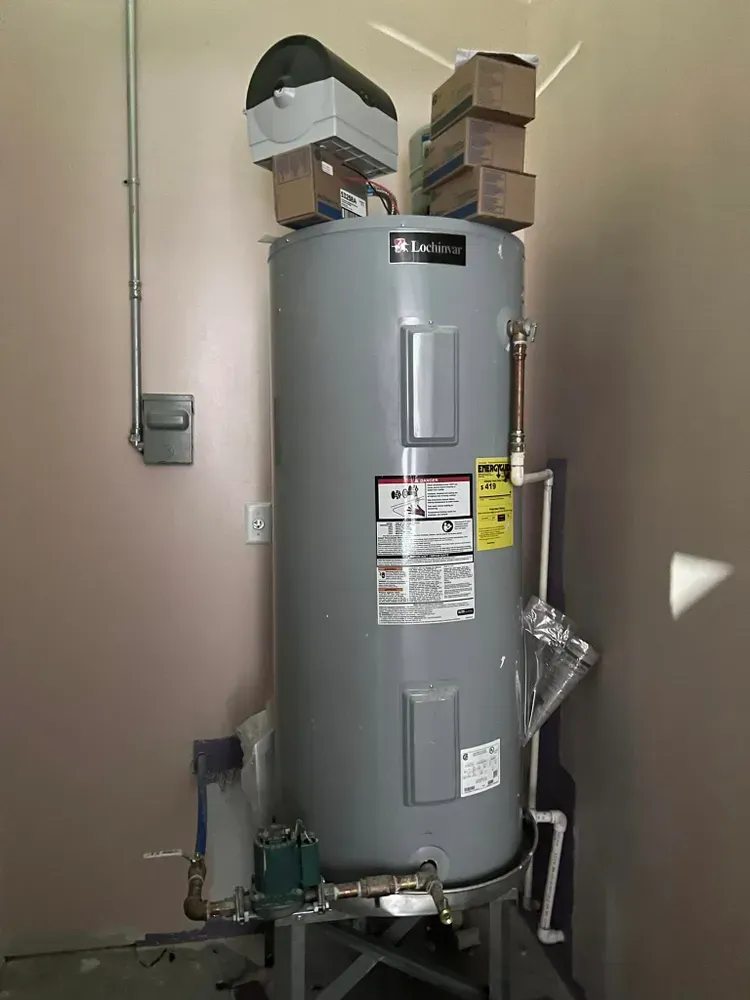 A large gray water heater is sitting in a room next to a wall.