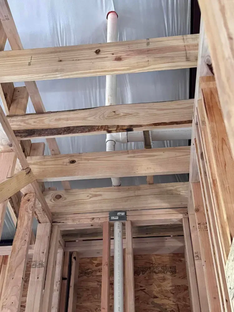 A bathroom under construction with wooden beams and pipes.