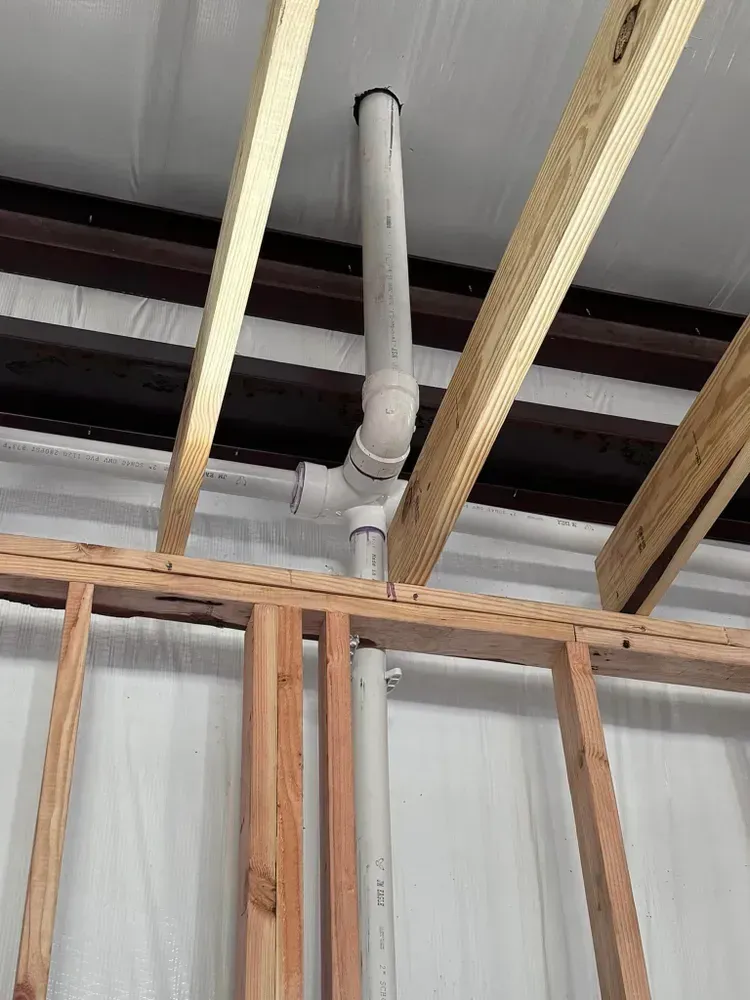 A pipe is hanging from the ceiling of a building under construction.