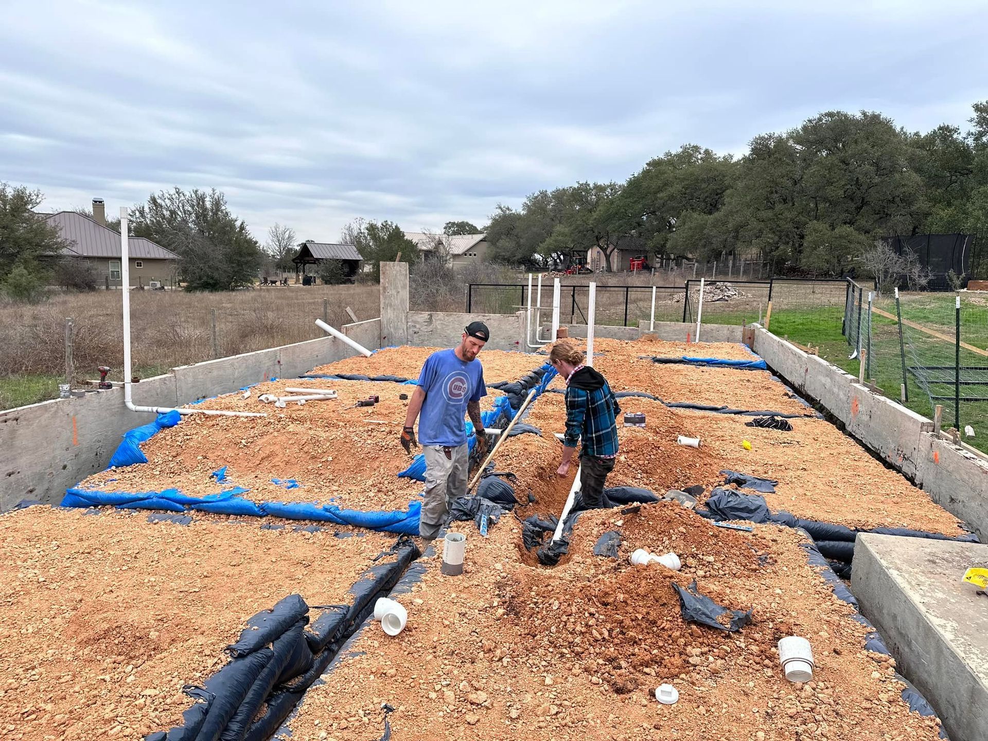 Two men are digging in a pile of dirt.