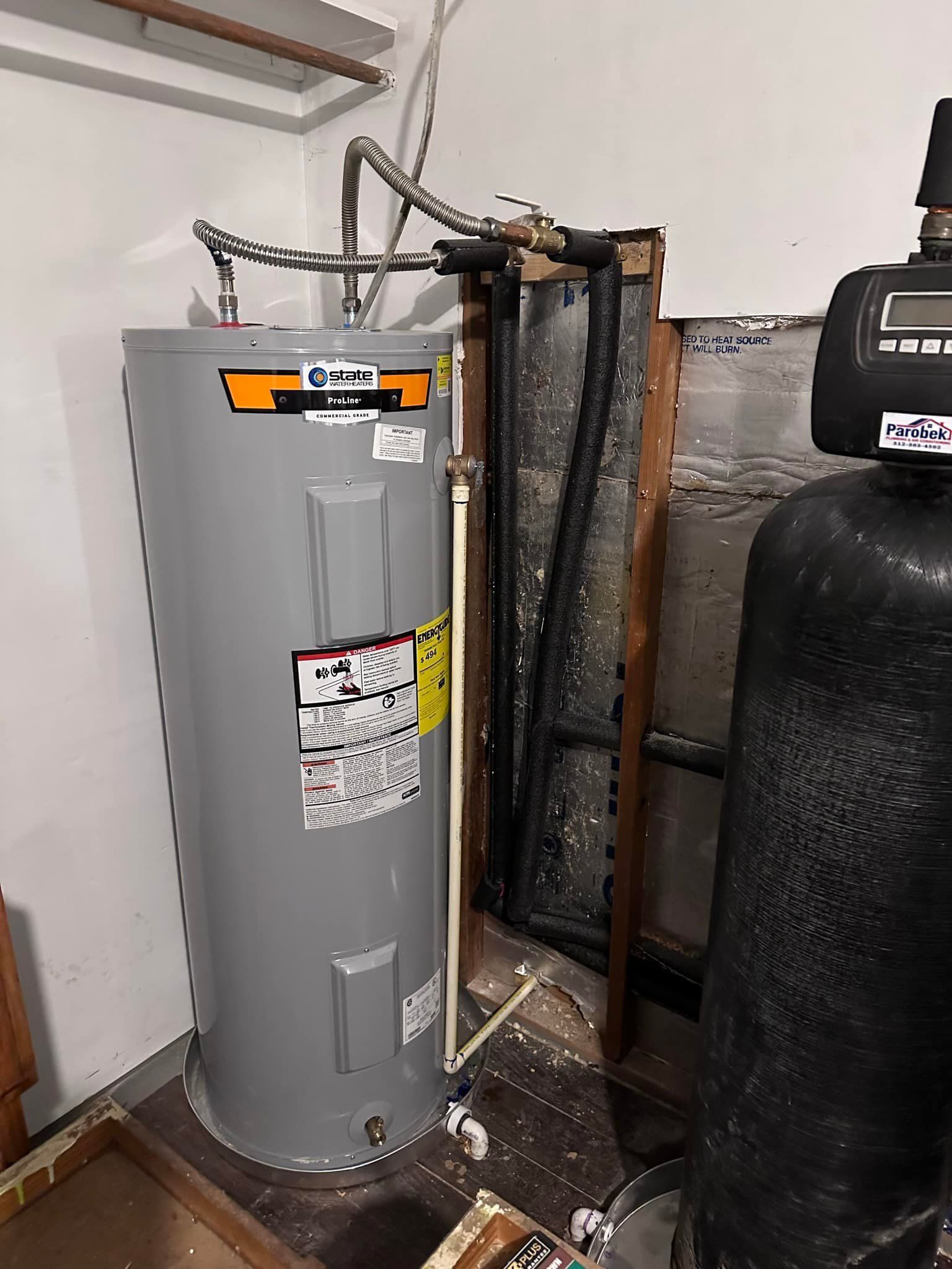 A water heater is sitting in a room next to a water filter.