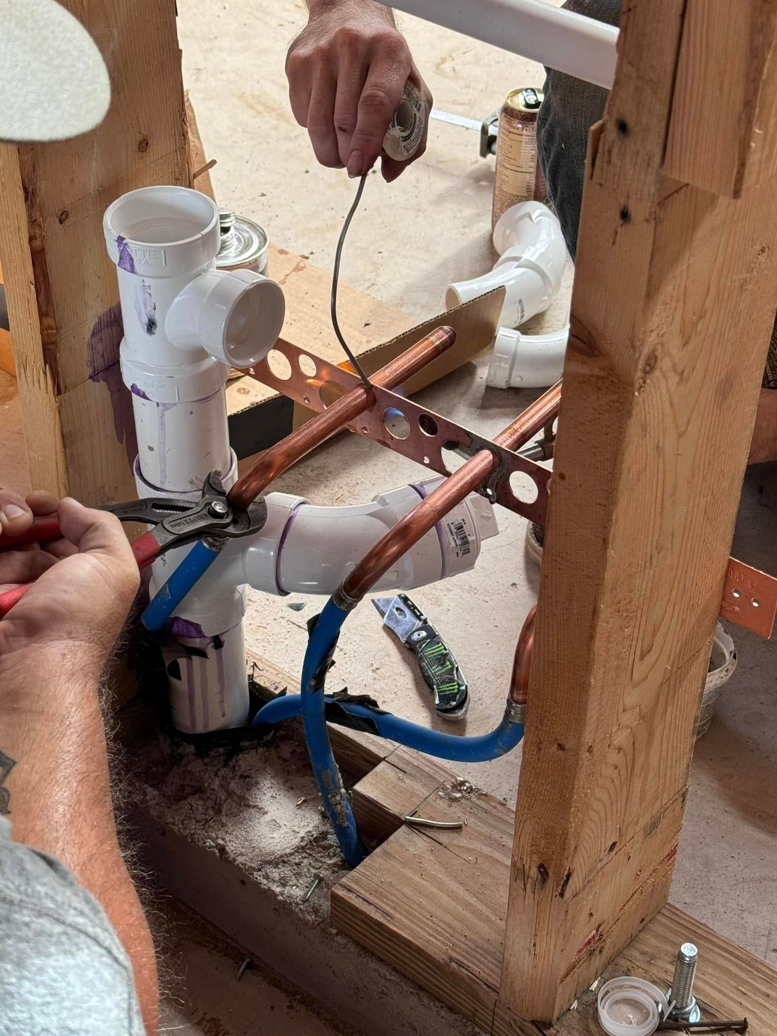 A man is working on a pipe with a pair of pliers.