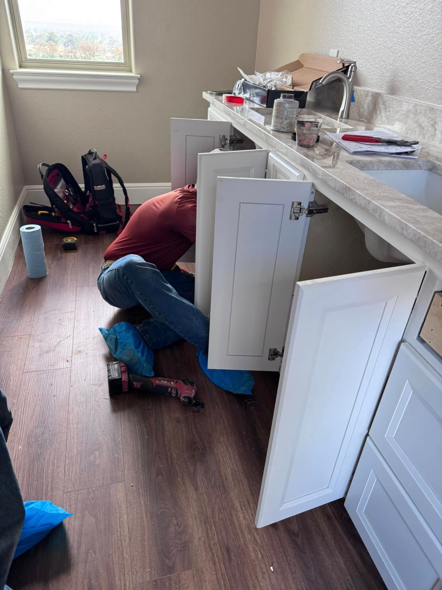 A man is working under a sink in a kitchen.