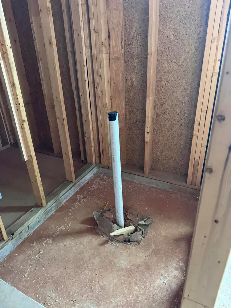 A pipe is sitting in the middle of a room in a house under construction.