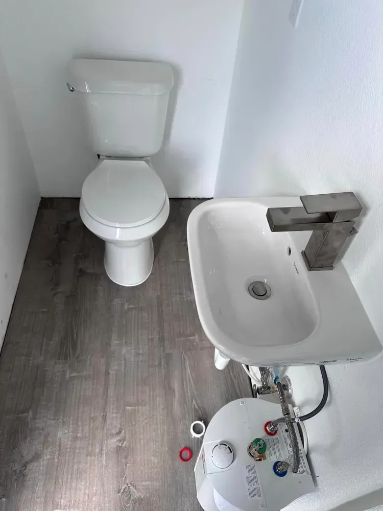 A bathroom with a toilet , sink and faucet.