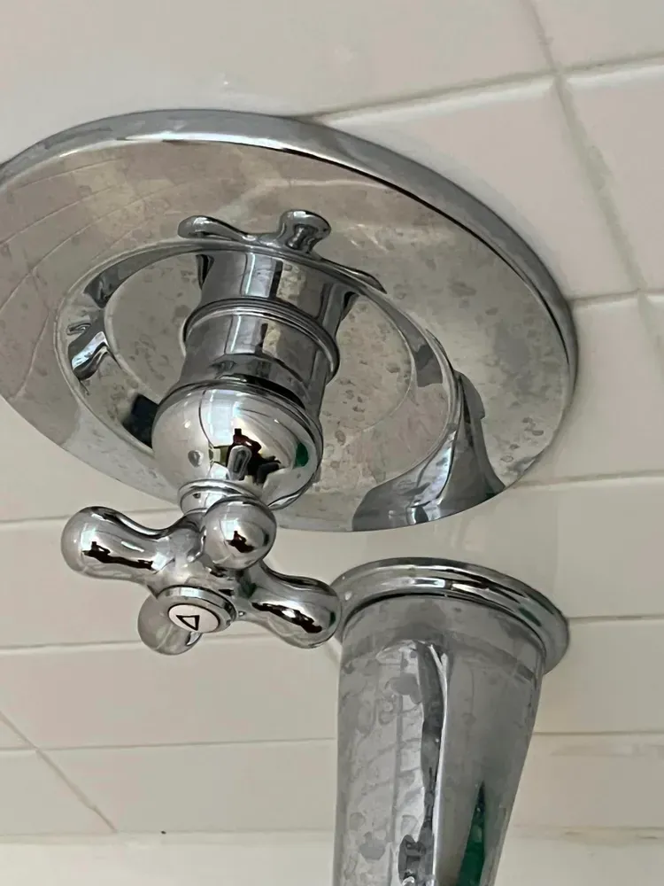 A close up of a chrome shower head hanging from the ceiling.