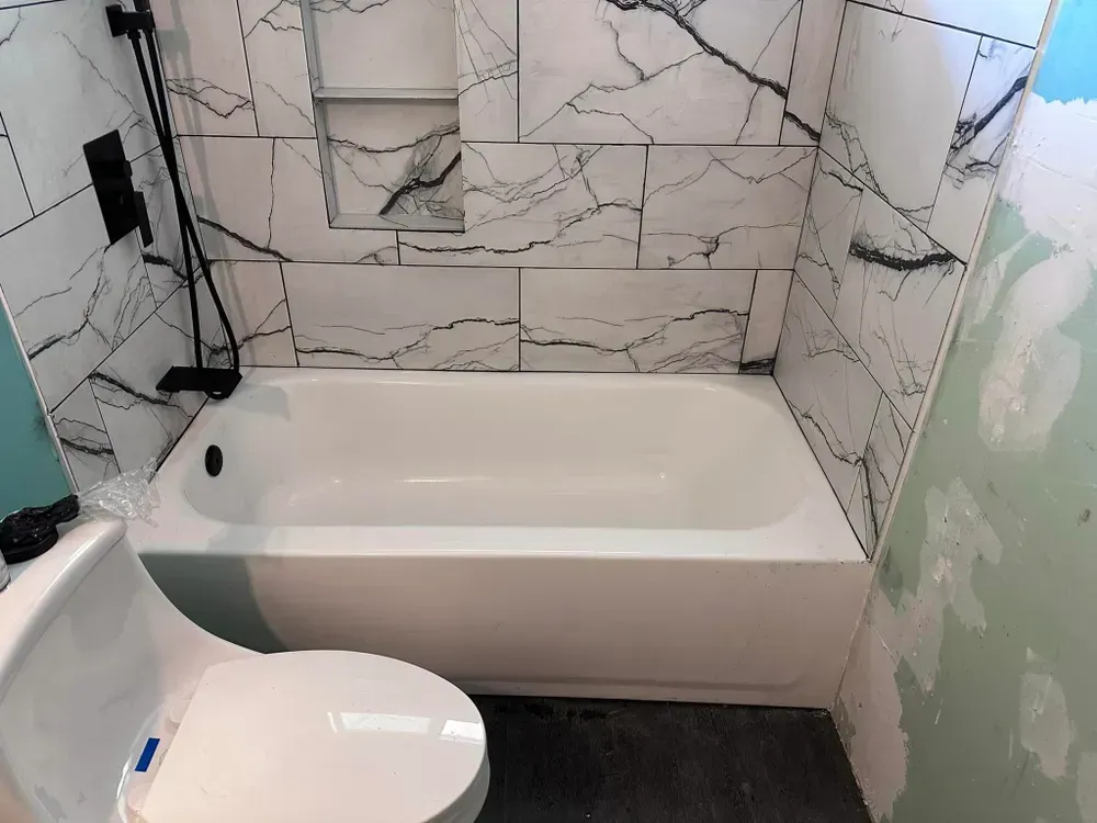 A bathroom with a bathtub , toilet and shower.