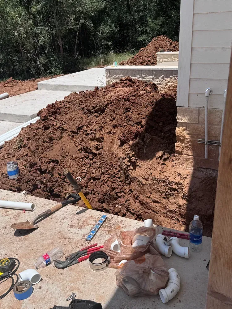 A pile of dirt is sitting on a concrete surface next to a house.