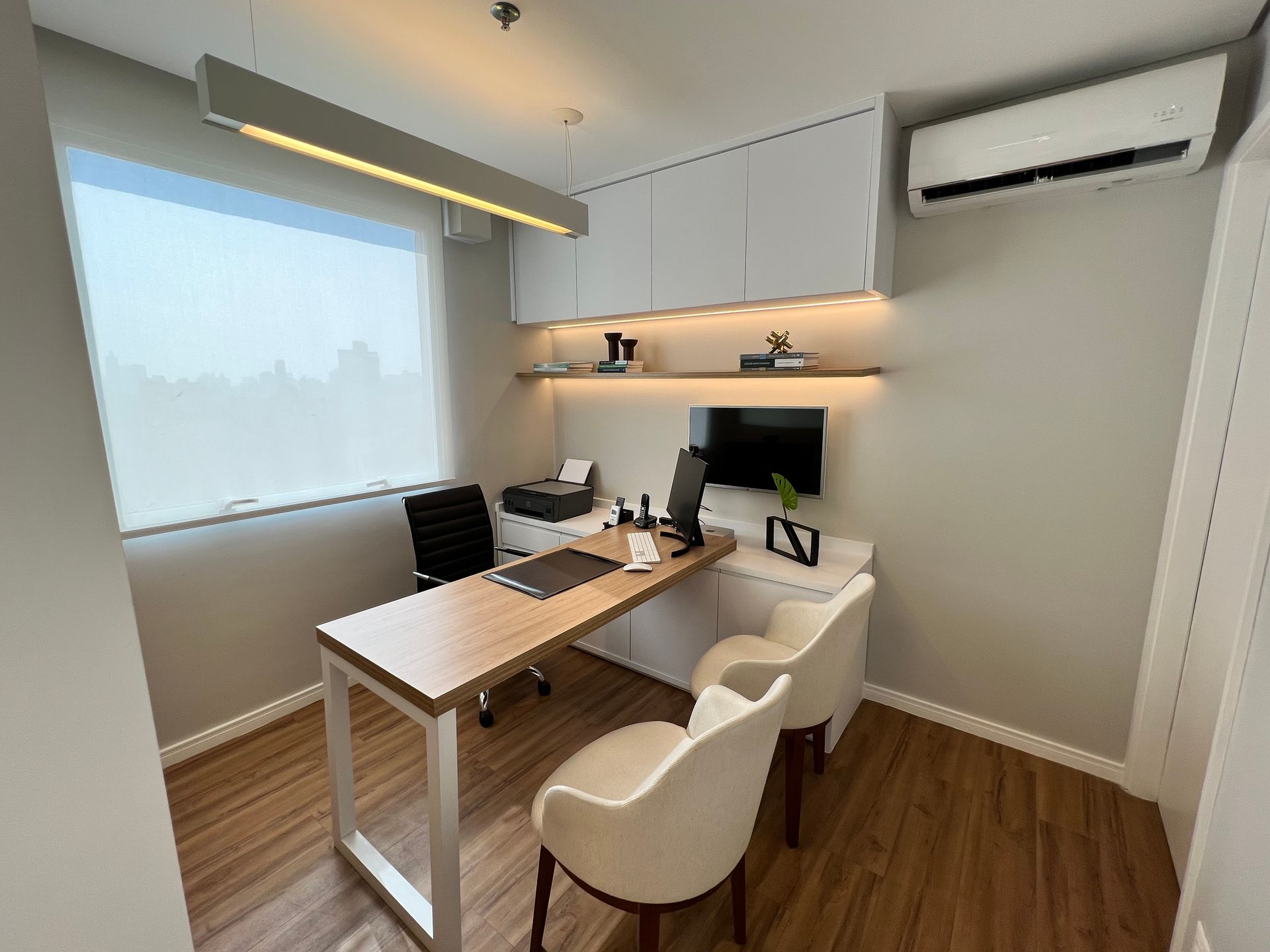 Um pequeno escritório com uma mesa, cadeiras e um computador.