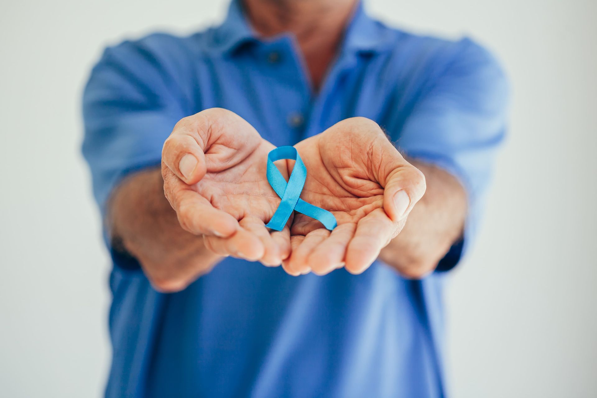 Um homem está segurando uma fita azul nas mãos.