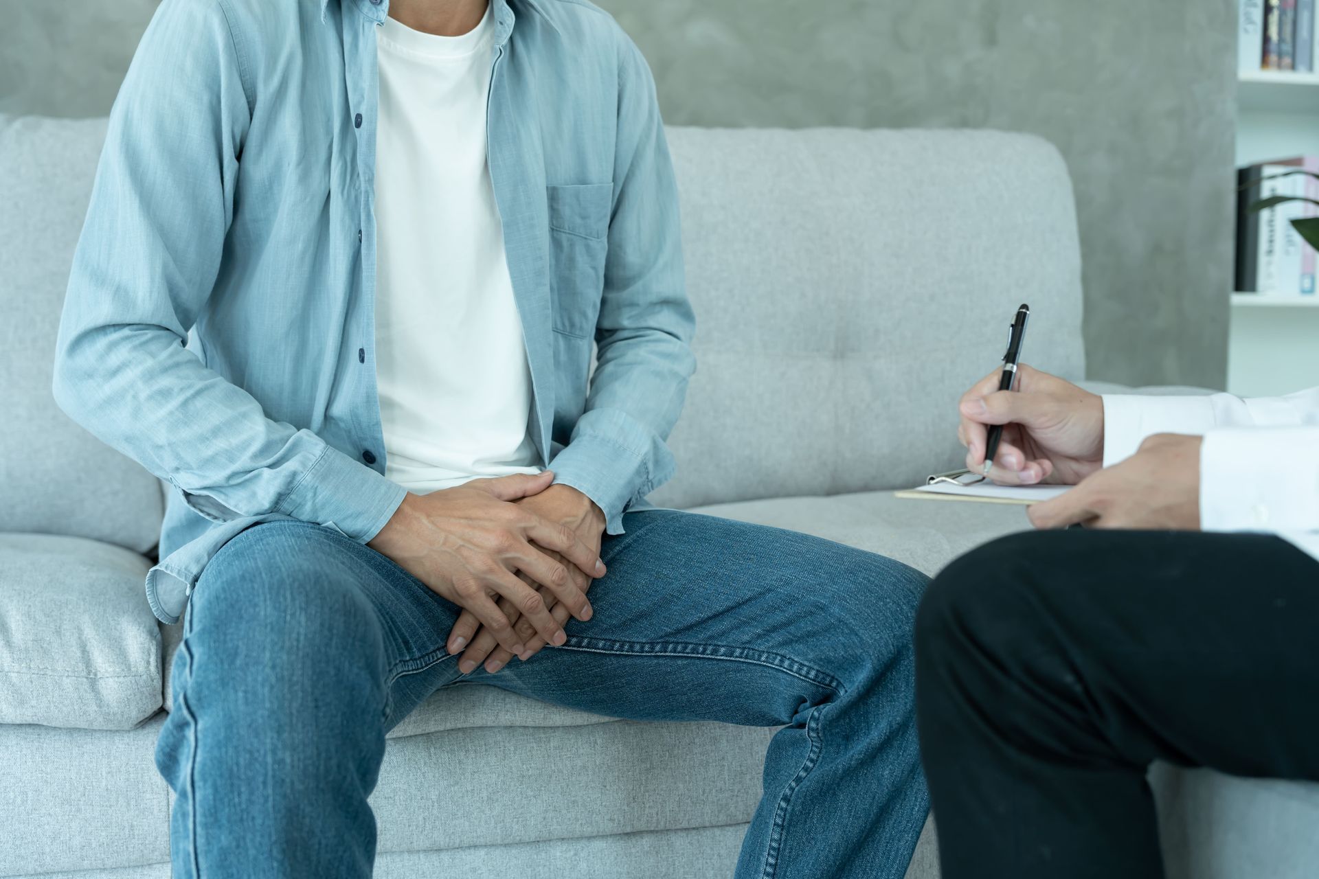Um homem está sentado em um sofá conversando com um médico.