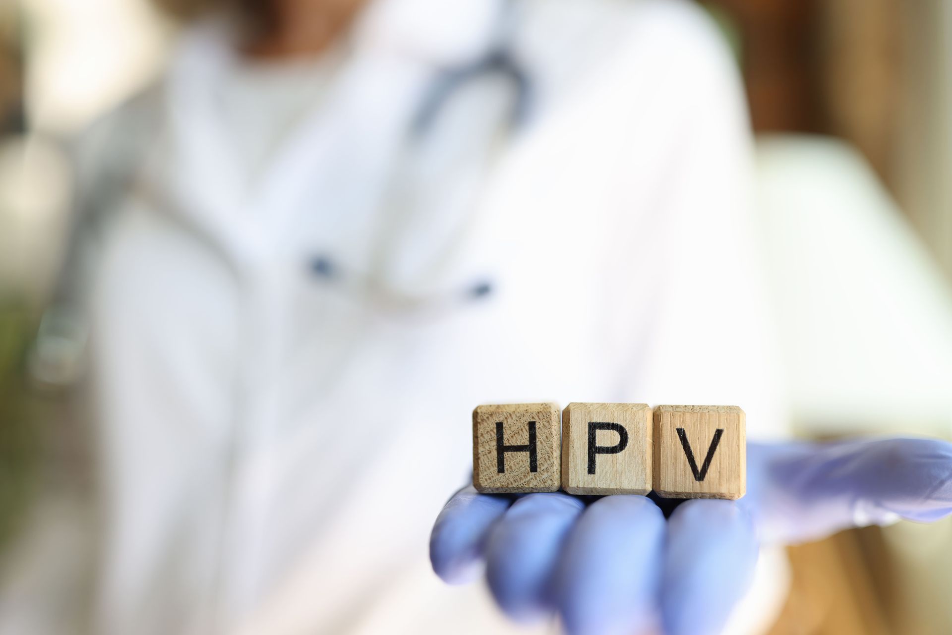 Um médico está segurando blocos de madeira com a palavra hpv escrita neles.