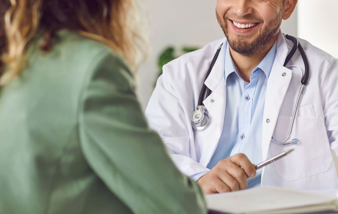 Um médico sorri enquanto fala com um paciente.