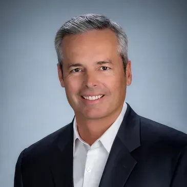 anthony clark from custom capital lending in a suit and white shirt is smiling for the camera.