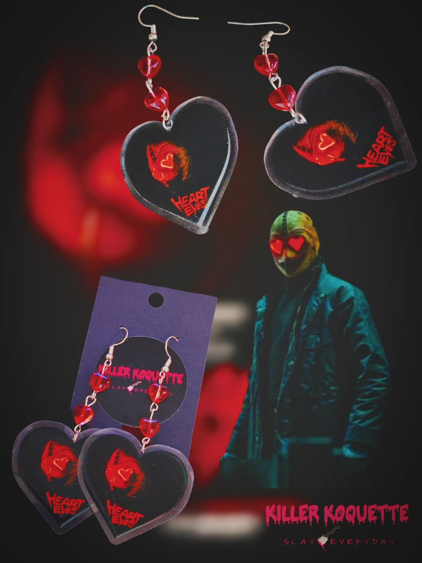Killer Koquette heart-shaped earrings featuring a hockey mask design, displayed with a masked figure in the background.