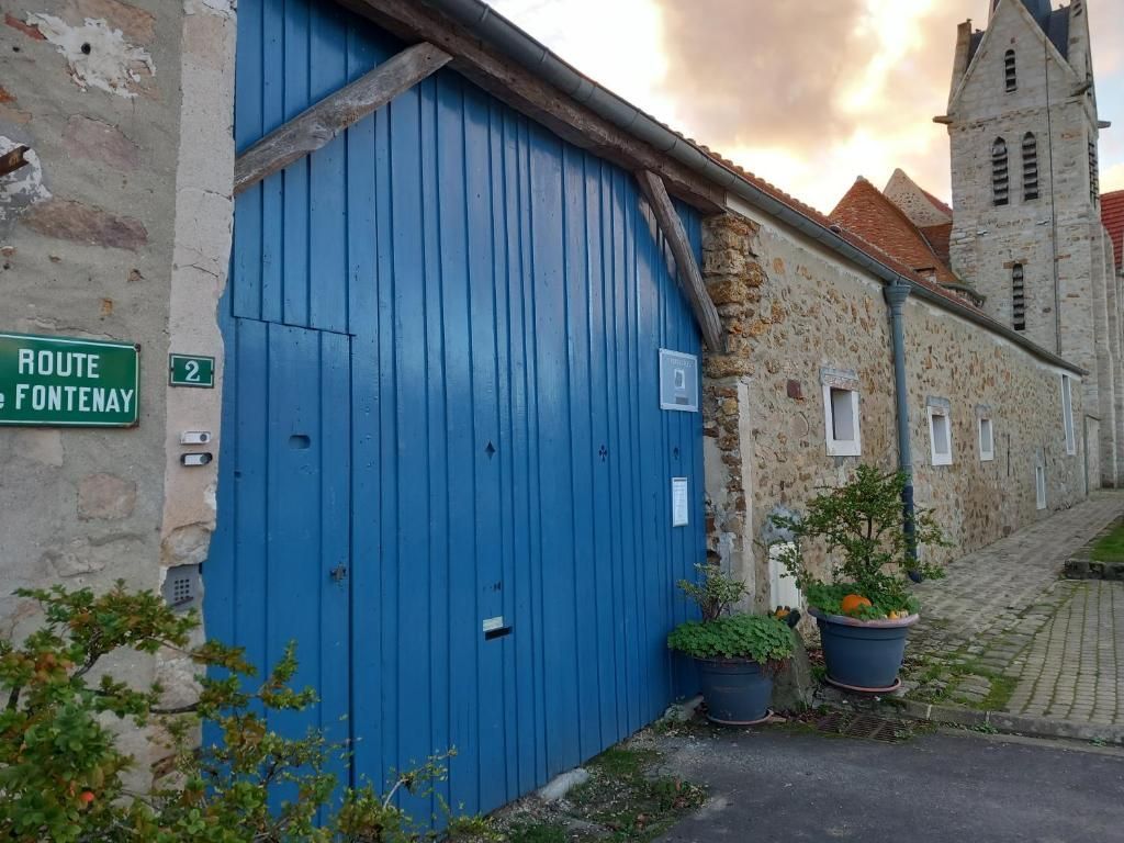 Une porte de garage bleue avec un panneau vert indiquant route fontenay