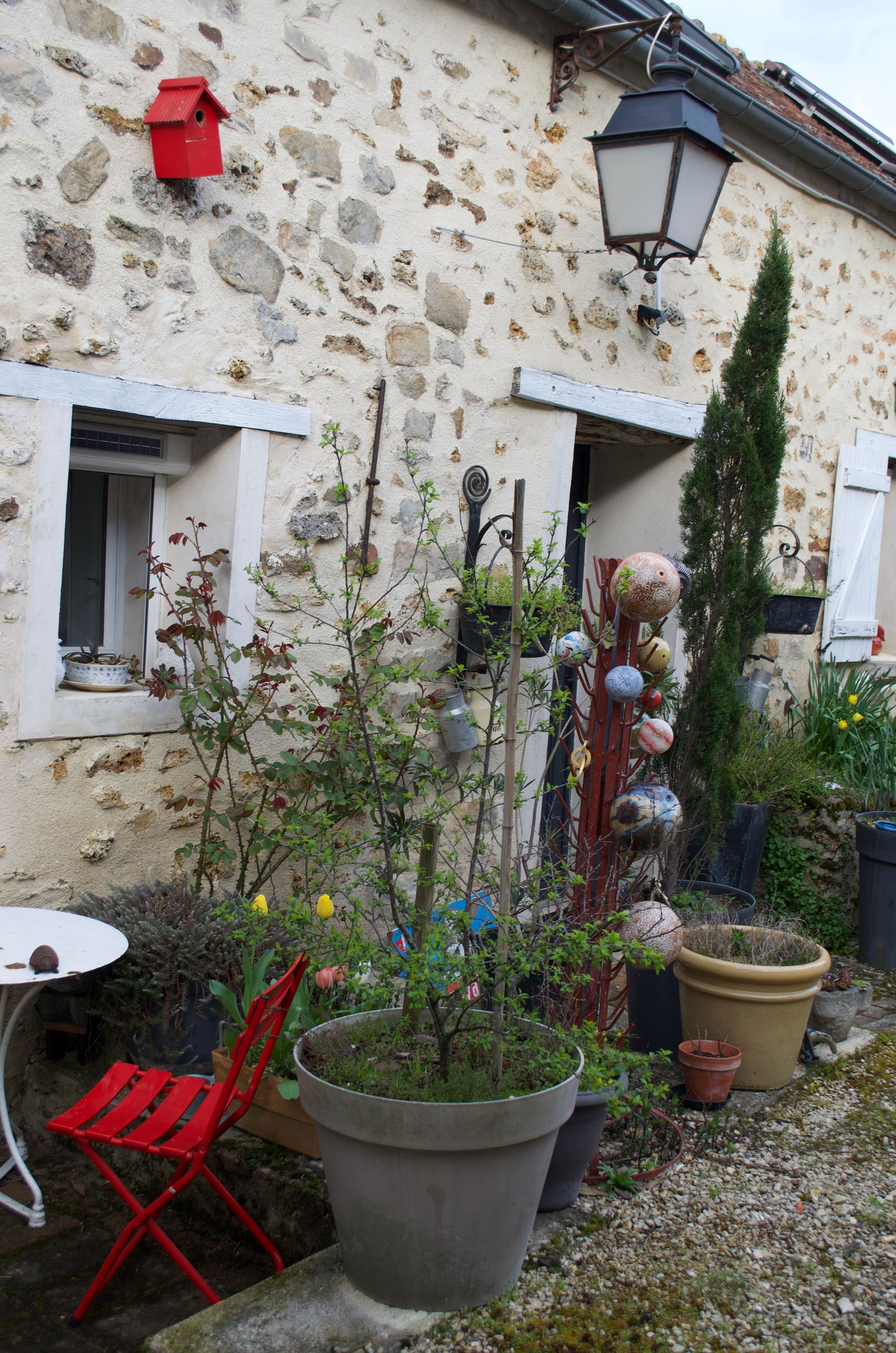 Un patio avec table et chaises devant un bâtiment en pierre.