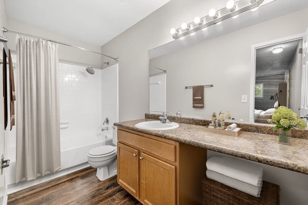 Apartment bathroom with a sink, toilet , shower, and mirror at Marquis at Perimeter Center in Atlanta, GA.