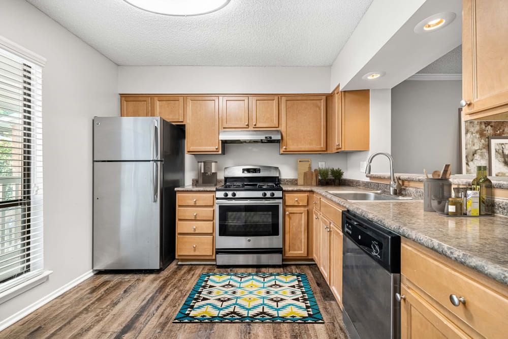Apartment kitchen with stainless steel appliances and wooden cabinets at Marquis at Perimeter Center in Atlanta, GA.