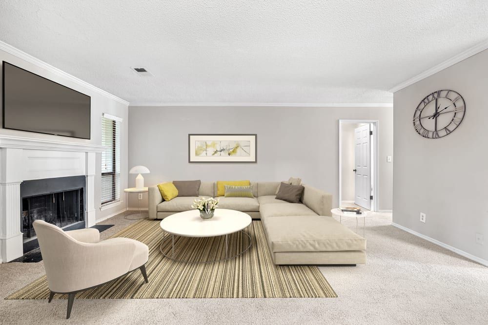 Modern apartment living room with a couch, chair, television, and fireplace at Marquis at Perimeter Center in Atlanta, GA.