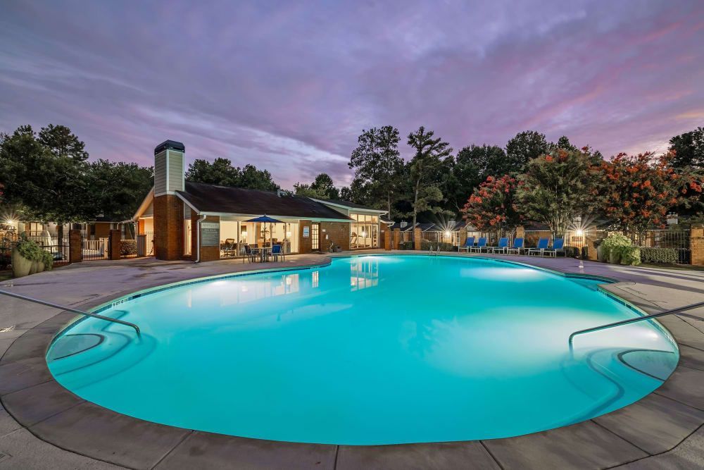 The apartment swimming pool is lit up at night in front of the clubhouse building at Marquis at Perimeter Center in Atlanta, GA.