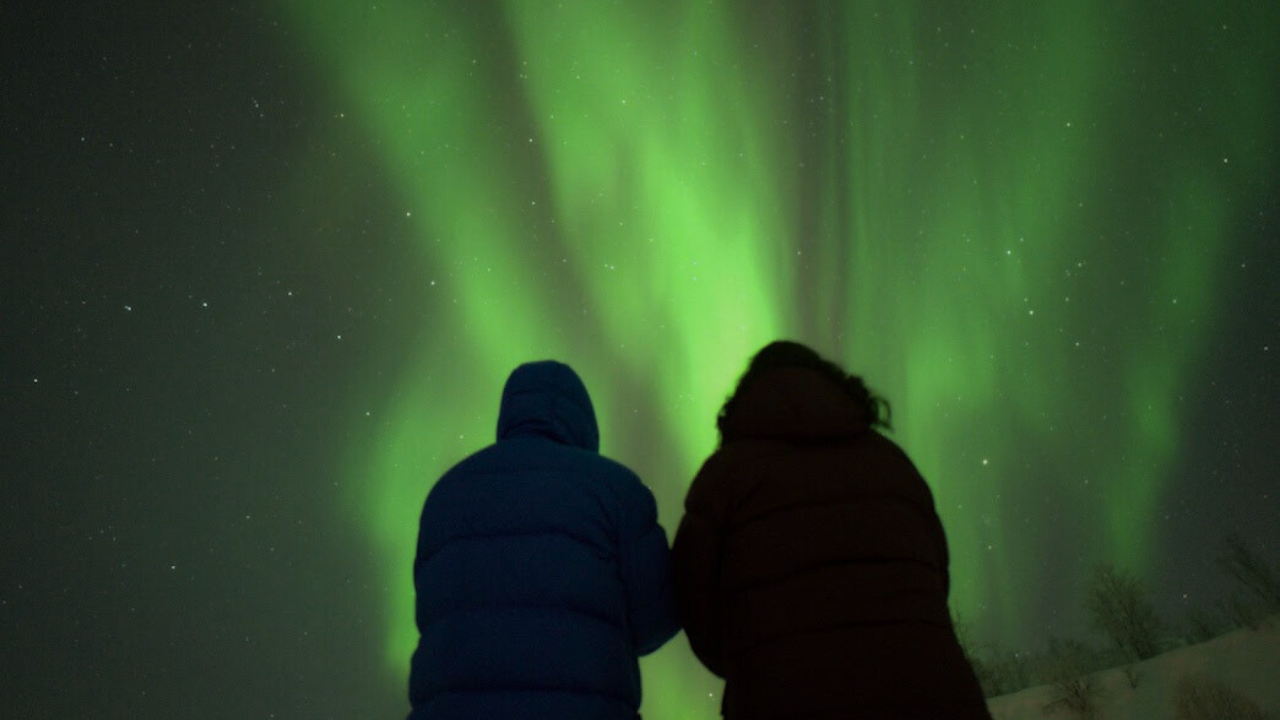 couples standing infront of northern light sky sky colored in green 