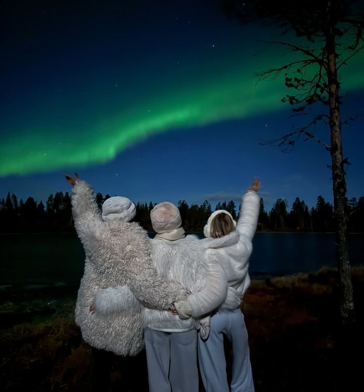couples dressed in winter clothes standing under aurora sky in tromso