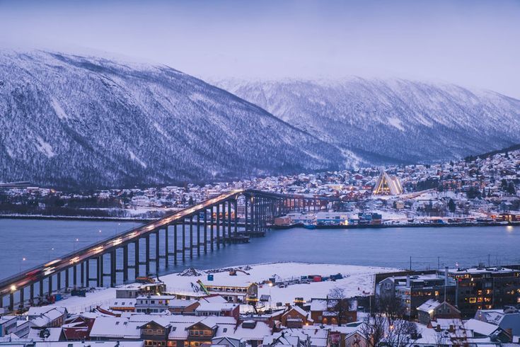 tromso bridge covered in snow and the mountain top covered in snow in the background