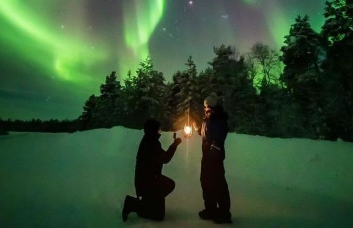 couples dressed in winter clothes standing under aurora sky in tromso