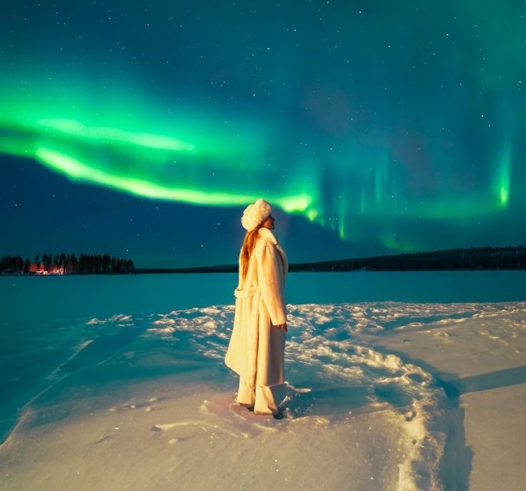 girl dressed in winter clothes standing under aurora sky in tromso