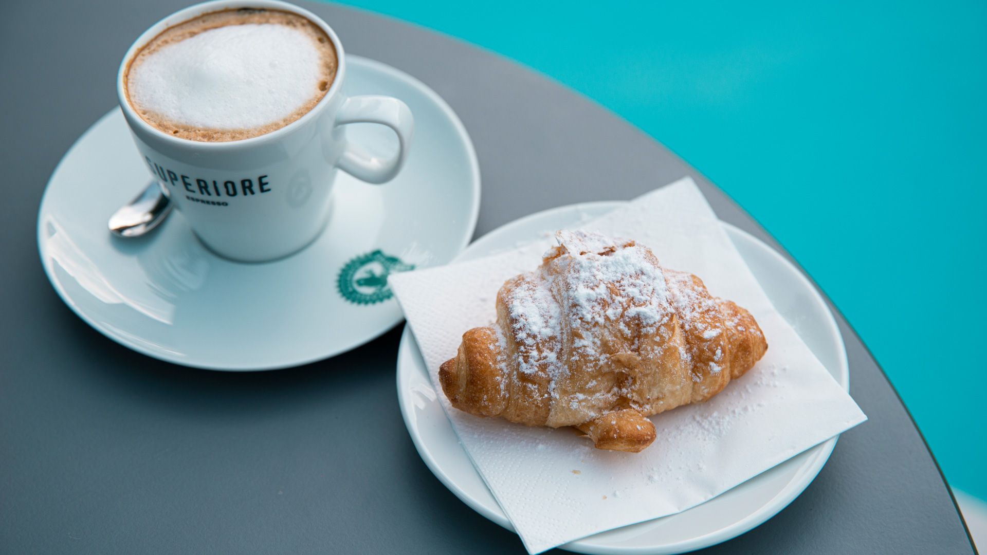Una tazza di caffè e un croissant su un piatto su un tavolo.