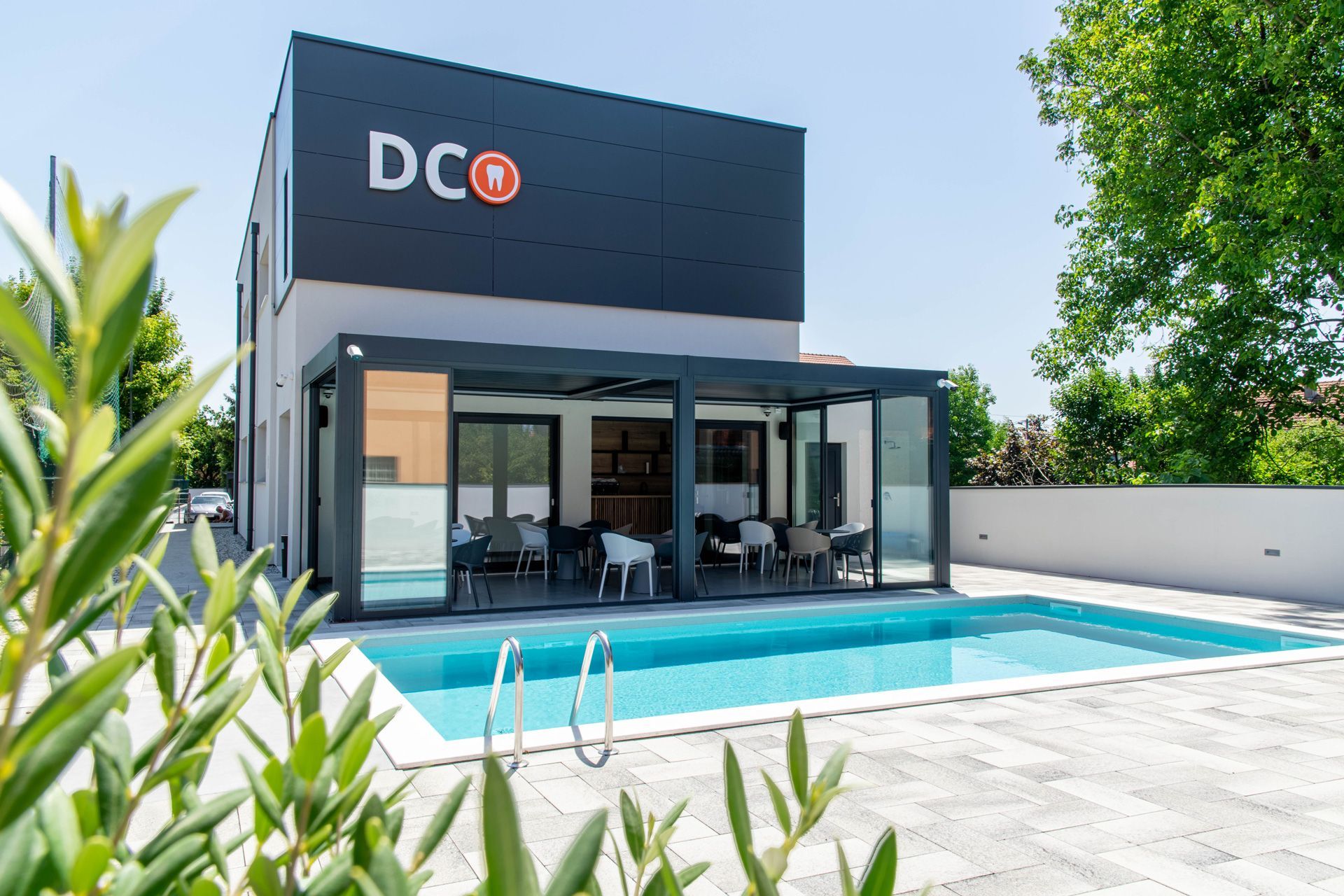 Una casa con piscina e un cartello con scritto studio dentistico Ostojic