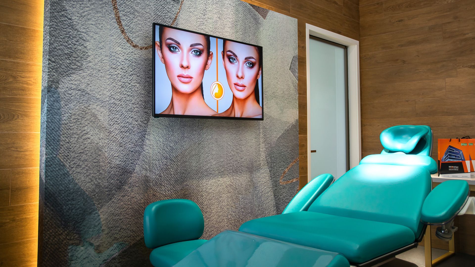 Una stanza con una sedia blu e un televisore alla parete.