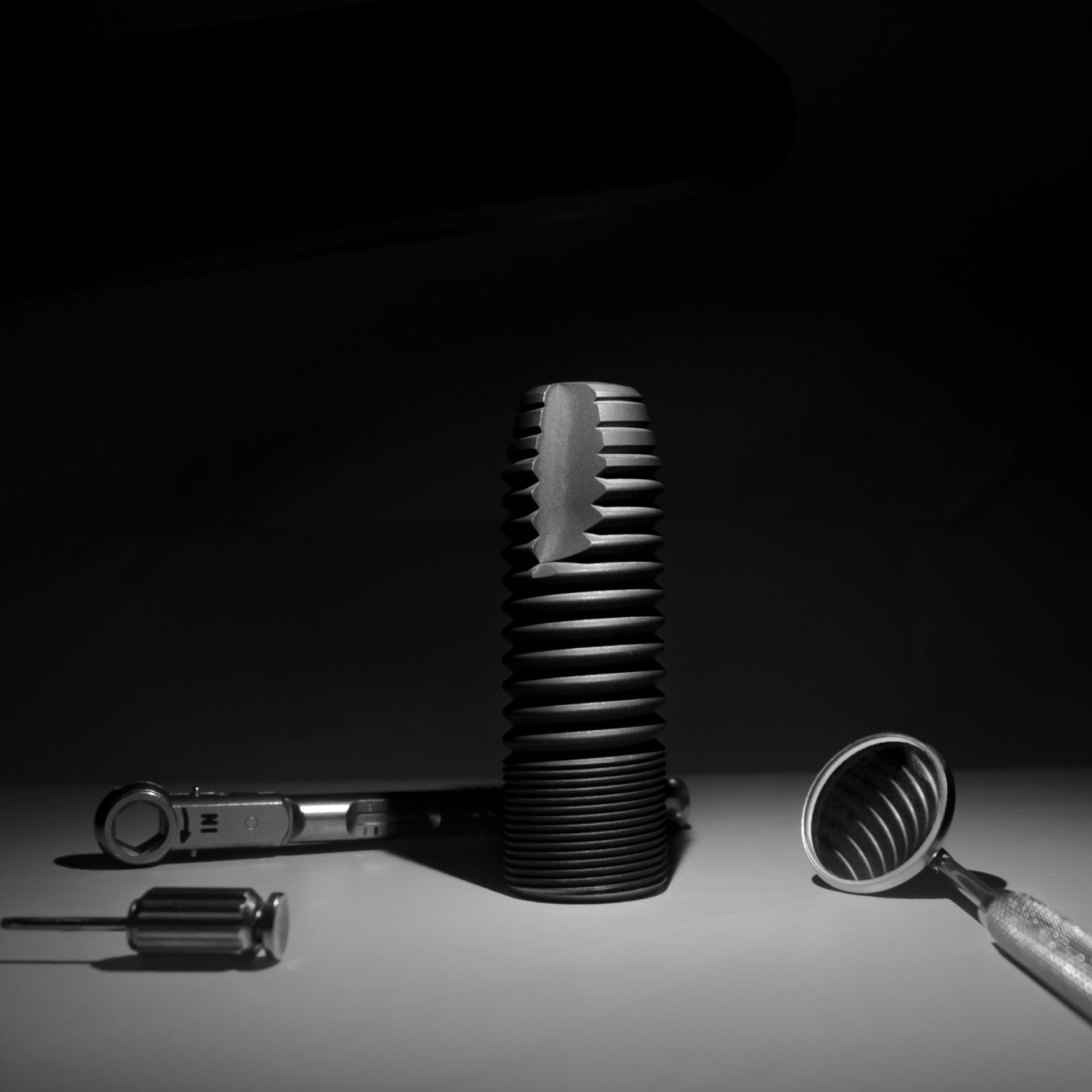 Una foto in bianco e nero di un microfono, un cacciavite e una tazza su un tavolo.