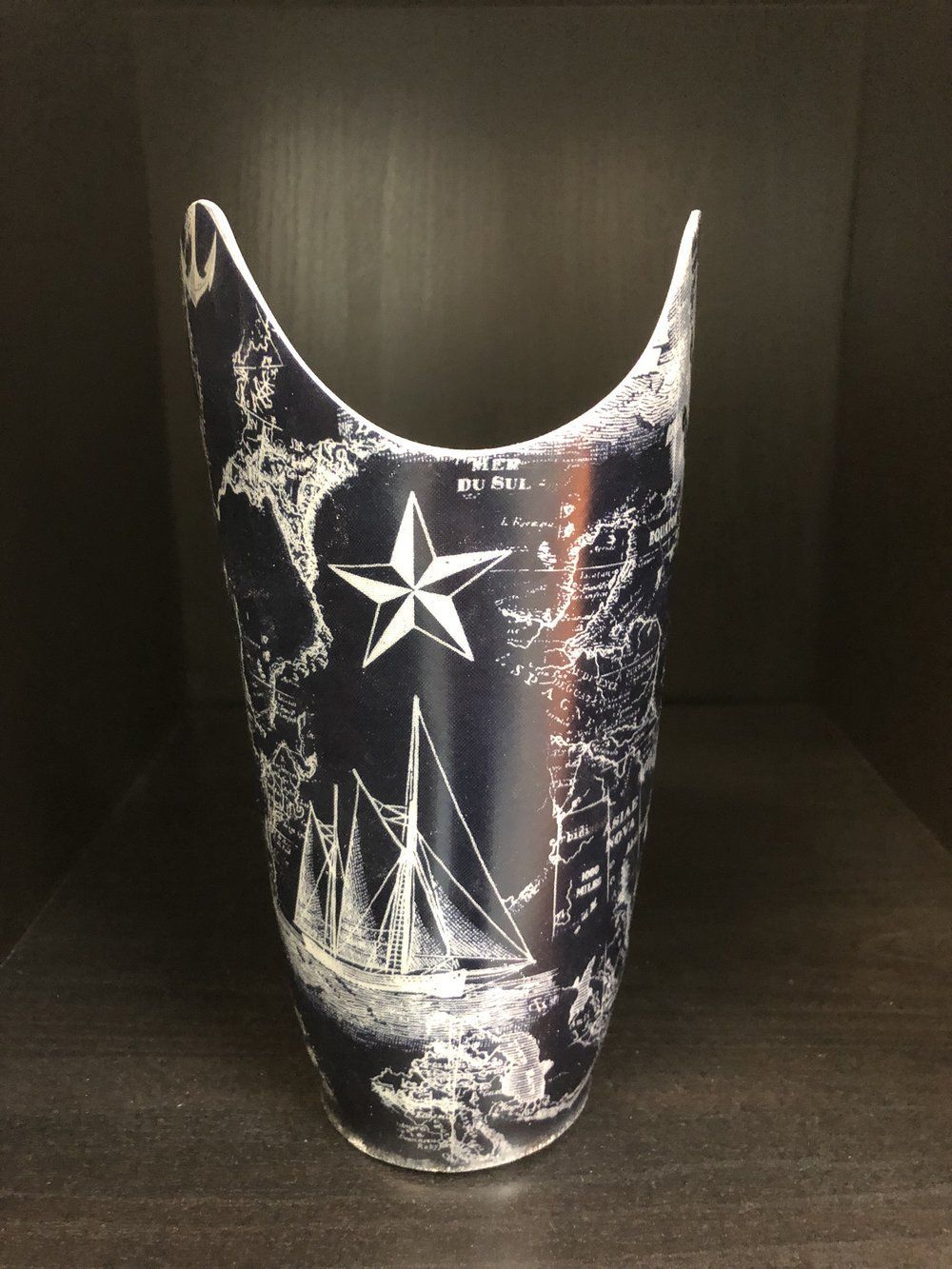 A black and white vase with a sailboat and star on it