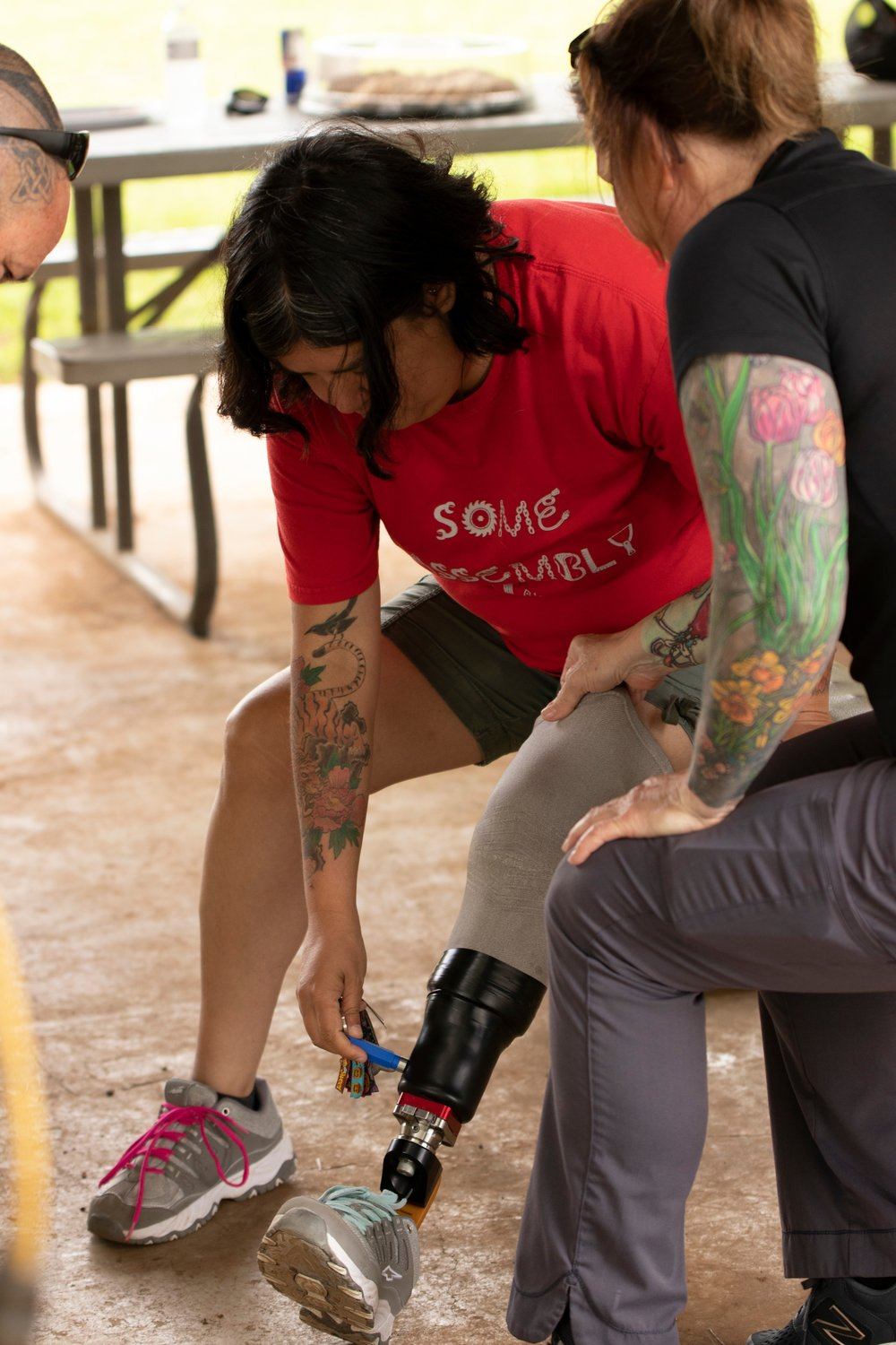 A woman with a prosthetic leg is putting on a shoe.