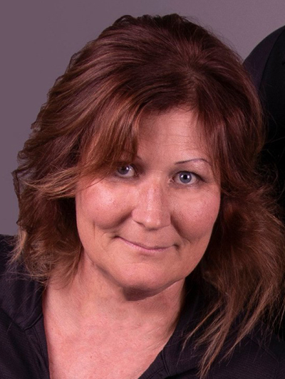 A woman with red hair and blue eyes is smiling for the camera.