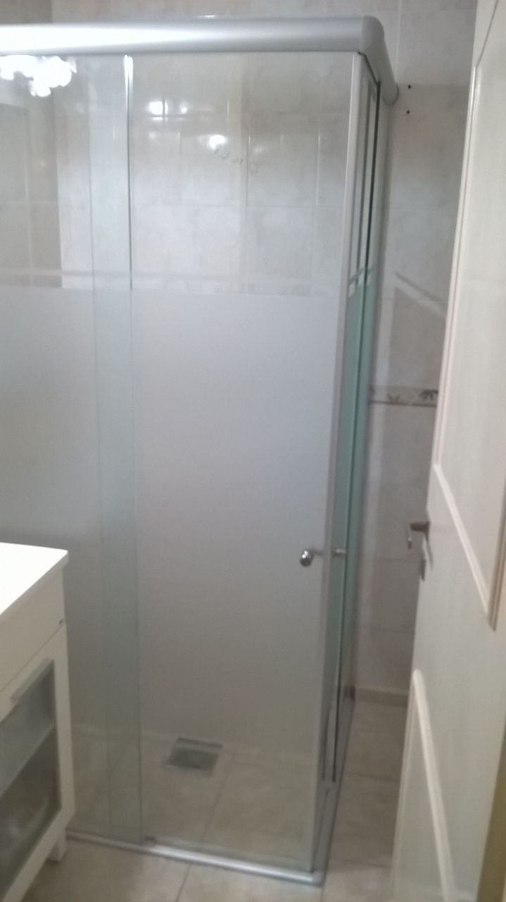 Un baño con mampara de ducha corredera de cristal y lavabo.