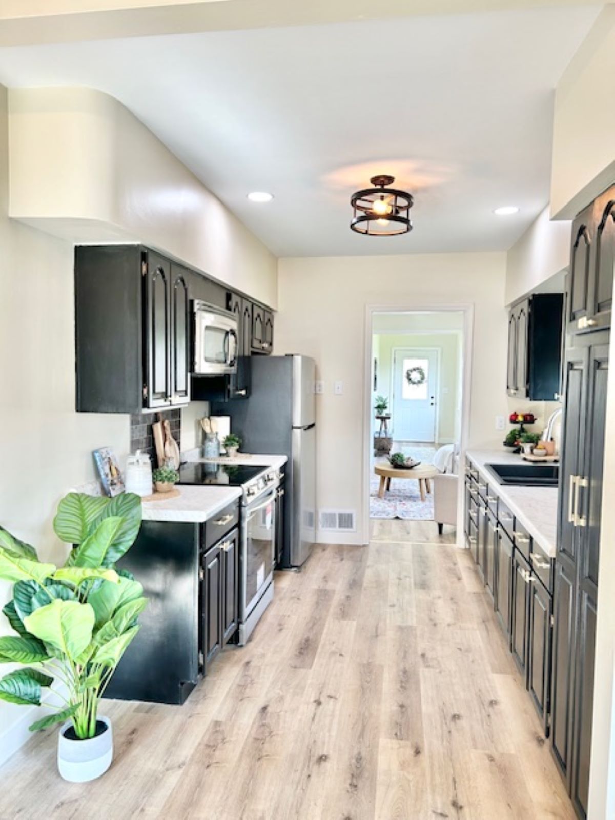 Black kitchen cabinets with white countertops and light wood floors.