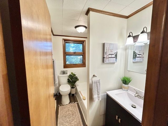 Bathroom interior with a sink, toilet, tub, and window; brown trim, white walls.