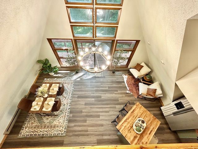 High-angle view of a living room with a chandelier, large windows, and seating areas.