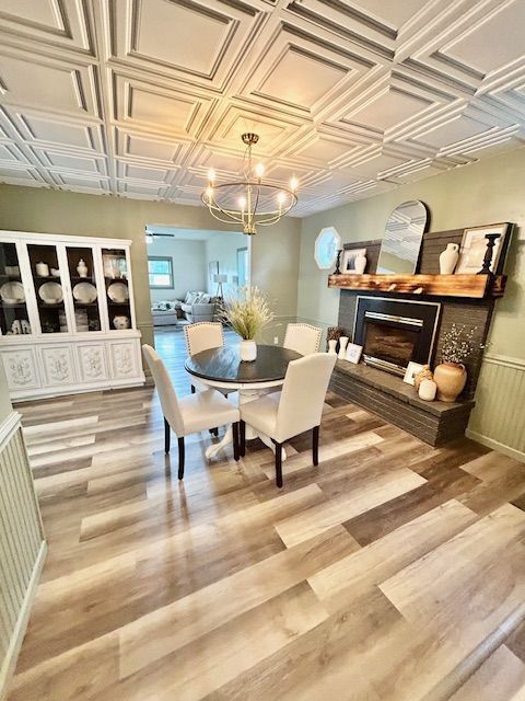 Dining room with coffered ceiling, chandelier, round table, fireplace, and hardwood flooring.