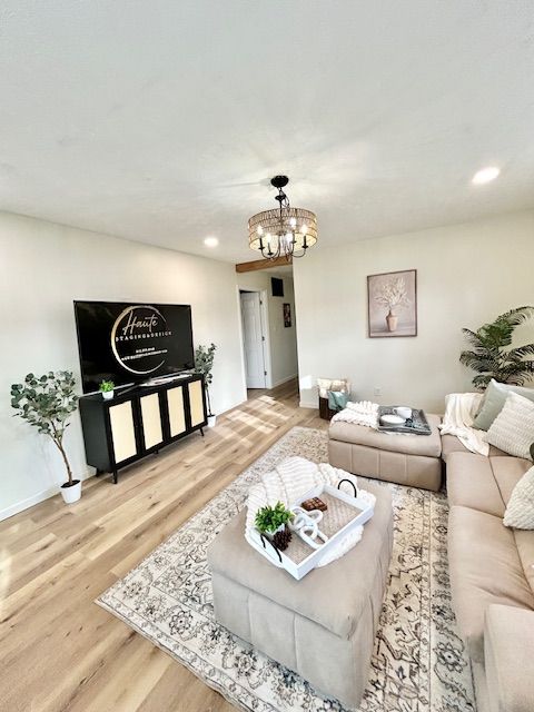 Living room with TV on black cabinet, tan sectional, area rug, and decorative tray.