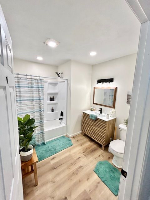 Bathroom with a wooden vanity, turquoise accents, and light wood-look flooring. White walls and door.