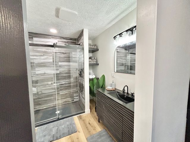 Modern bathroom with wood-look tile shower, dark vanity, and mirror, featuring neutral tones and a bright light.