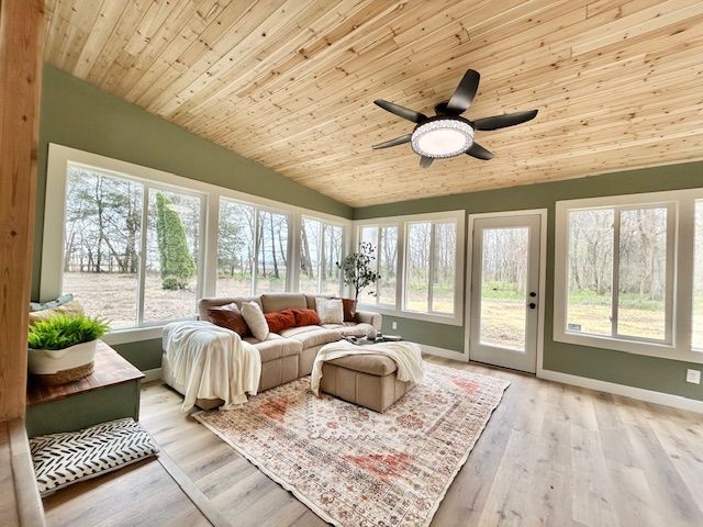 Sunroom with light wood ceiling and flooring, sage green walls, large windows, and a beige sofa.