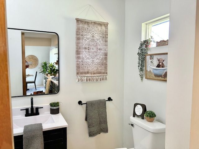 Bathroom with a black-framed mirror, white sink, and decorative rug hanging above the towel rack.