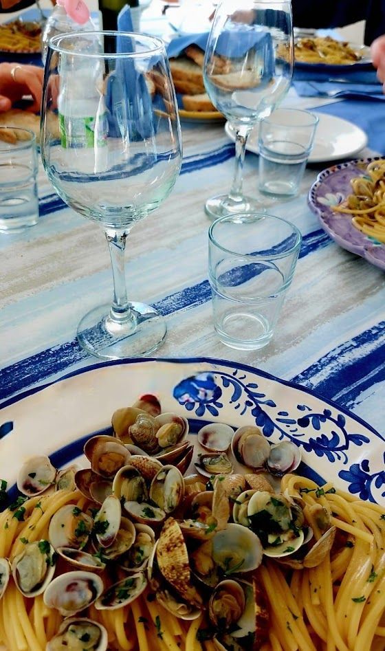 Un piatto con prosciutto affettato sottilmente e una grossa palla di mozzarella, accompagnato da una ciotolina di polpo marinato e limone.